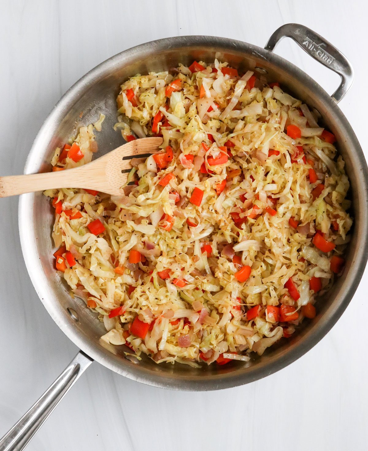 cooked shredded cabbage in skillet with wooden spoon