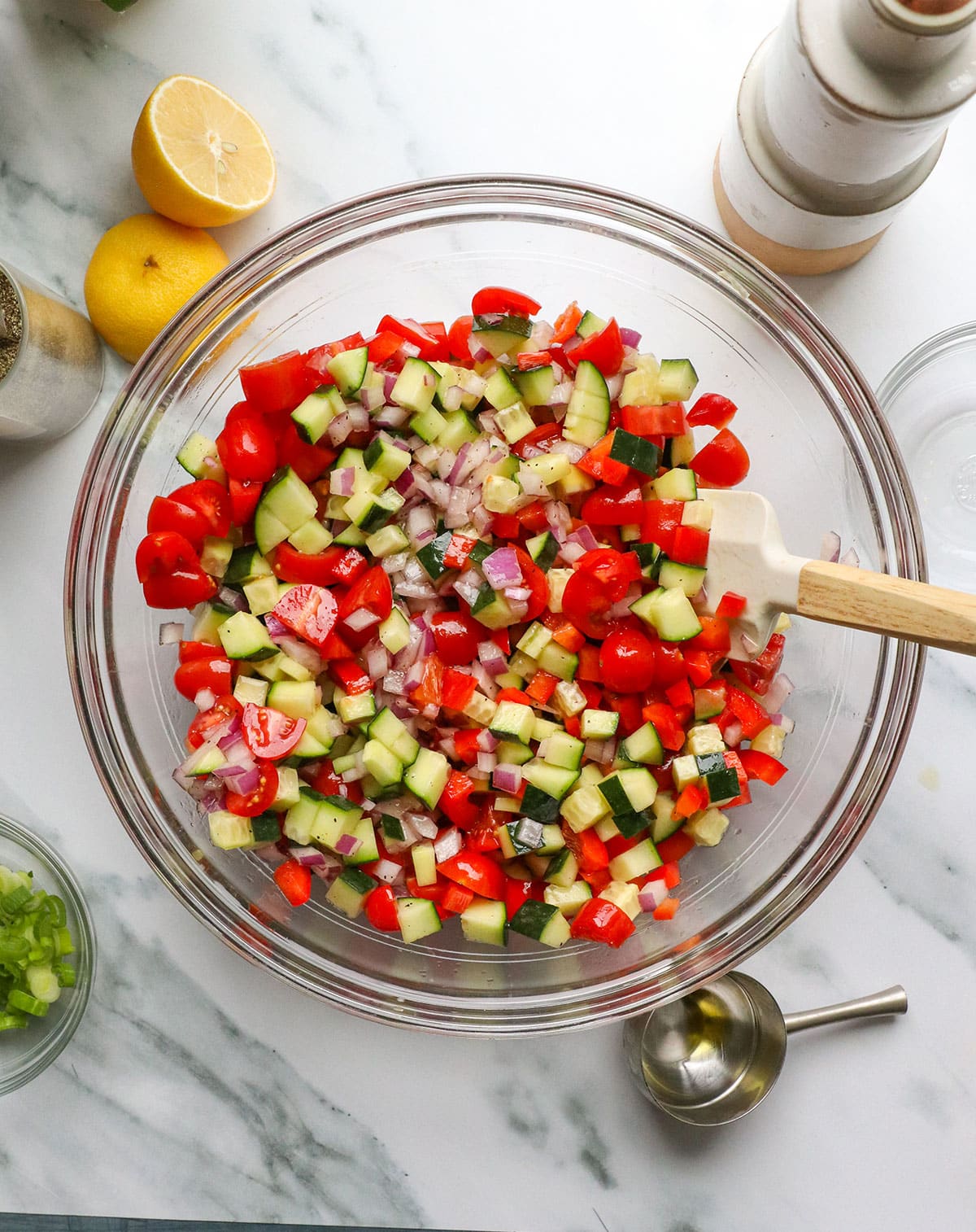 tomatoes, cucumbers and bell peppers stirred into the bowl of dressing.