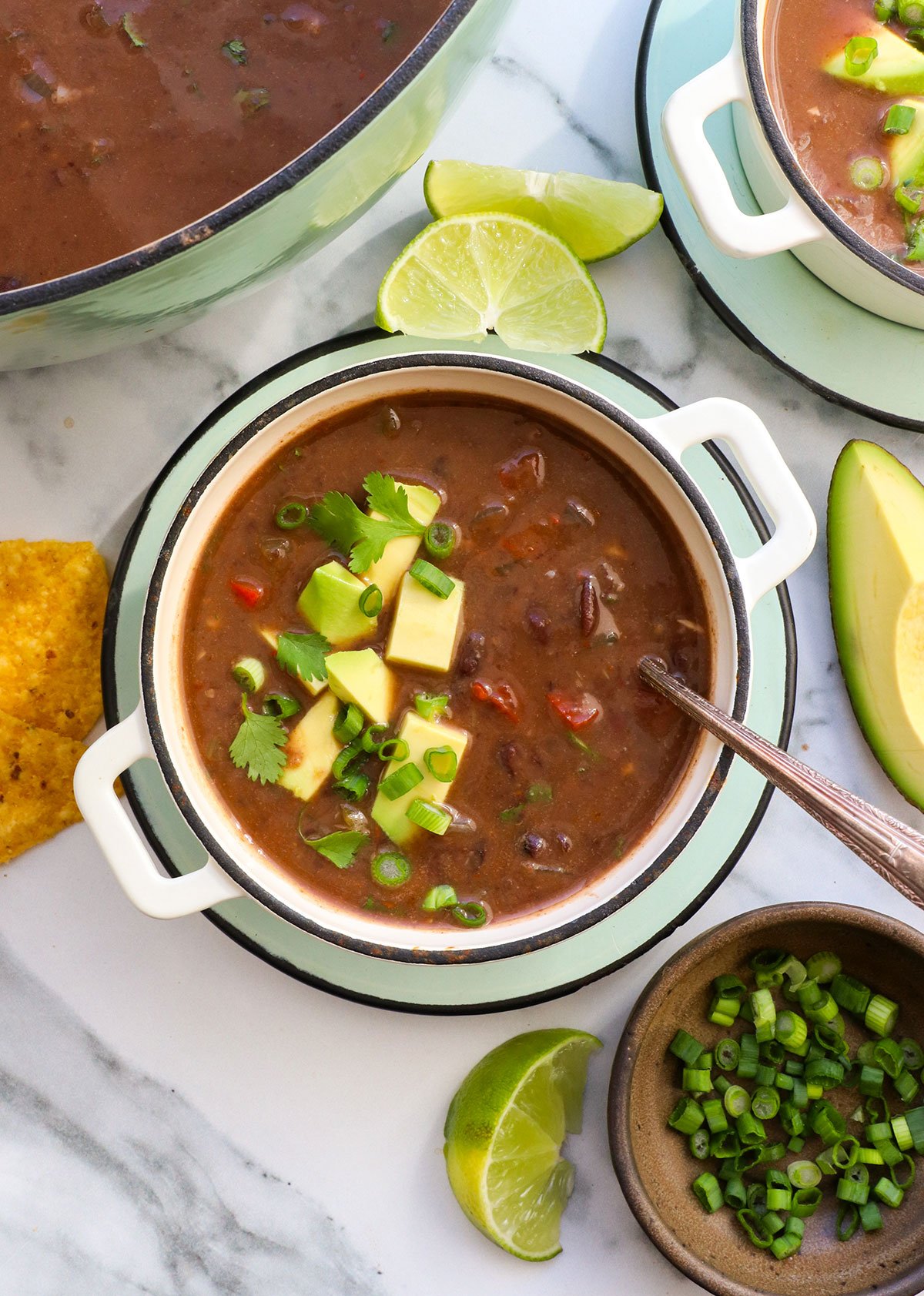 black bean soup in a bowl with avocado and cilantro served on top. 