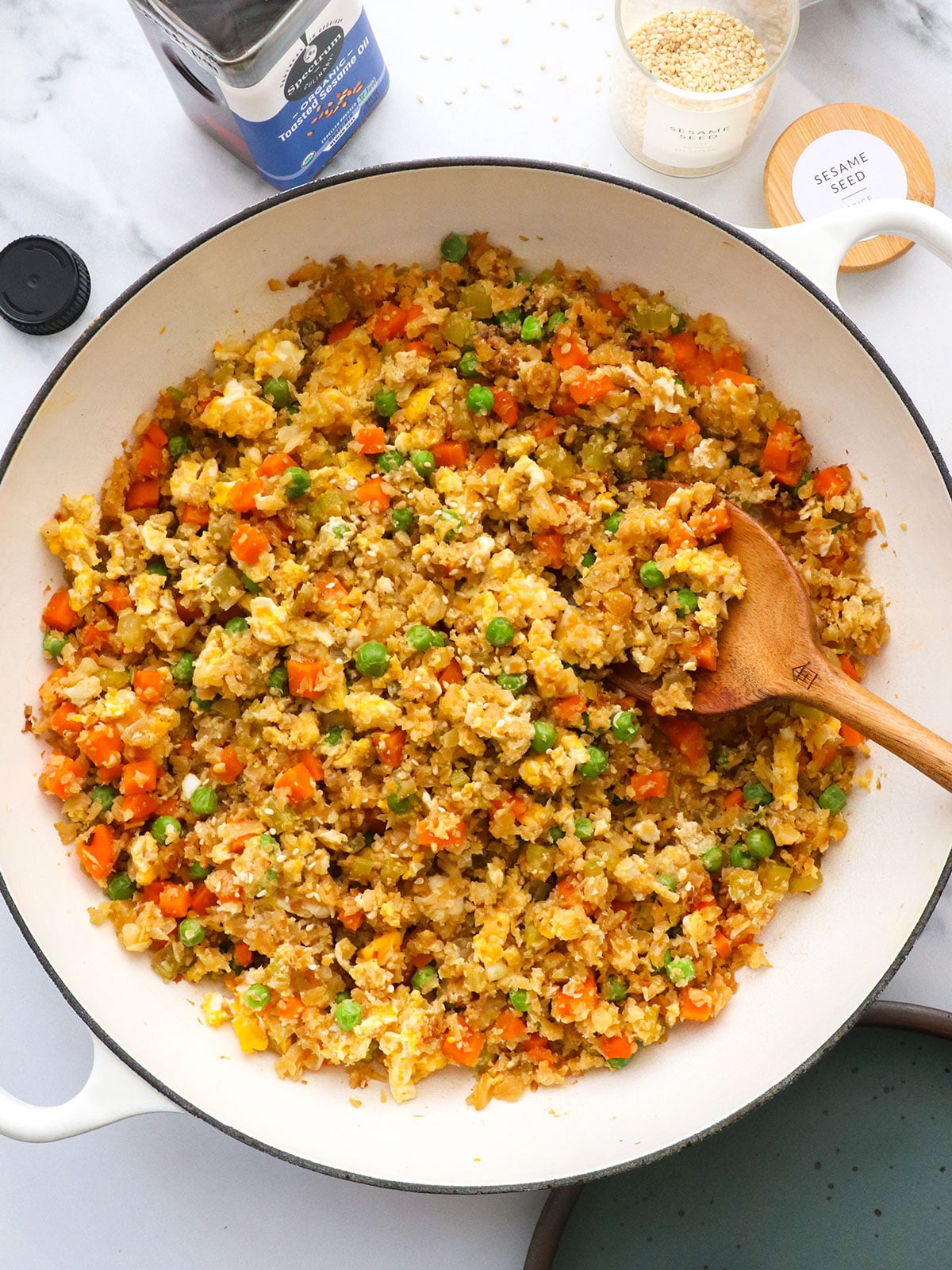 fluffy eggs stirred throughout cauliflower fried rice in a white pan. 