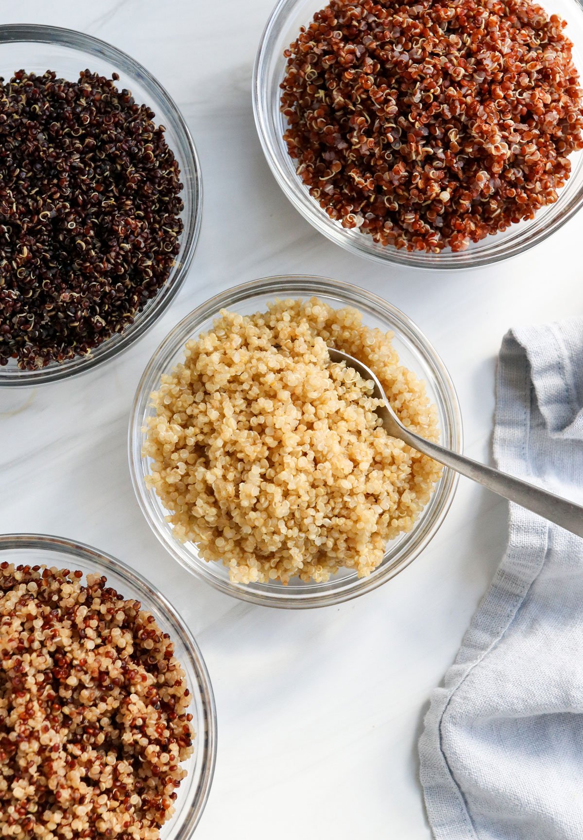 cooked colors of quinoa in glass bowls overhead.