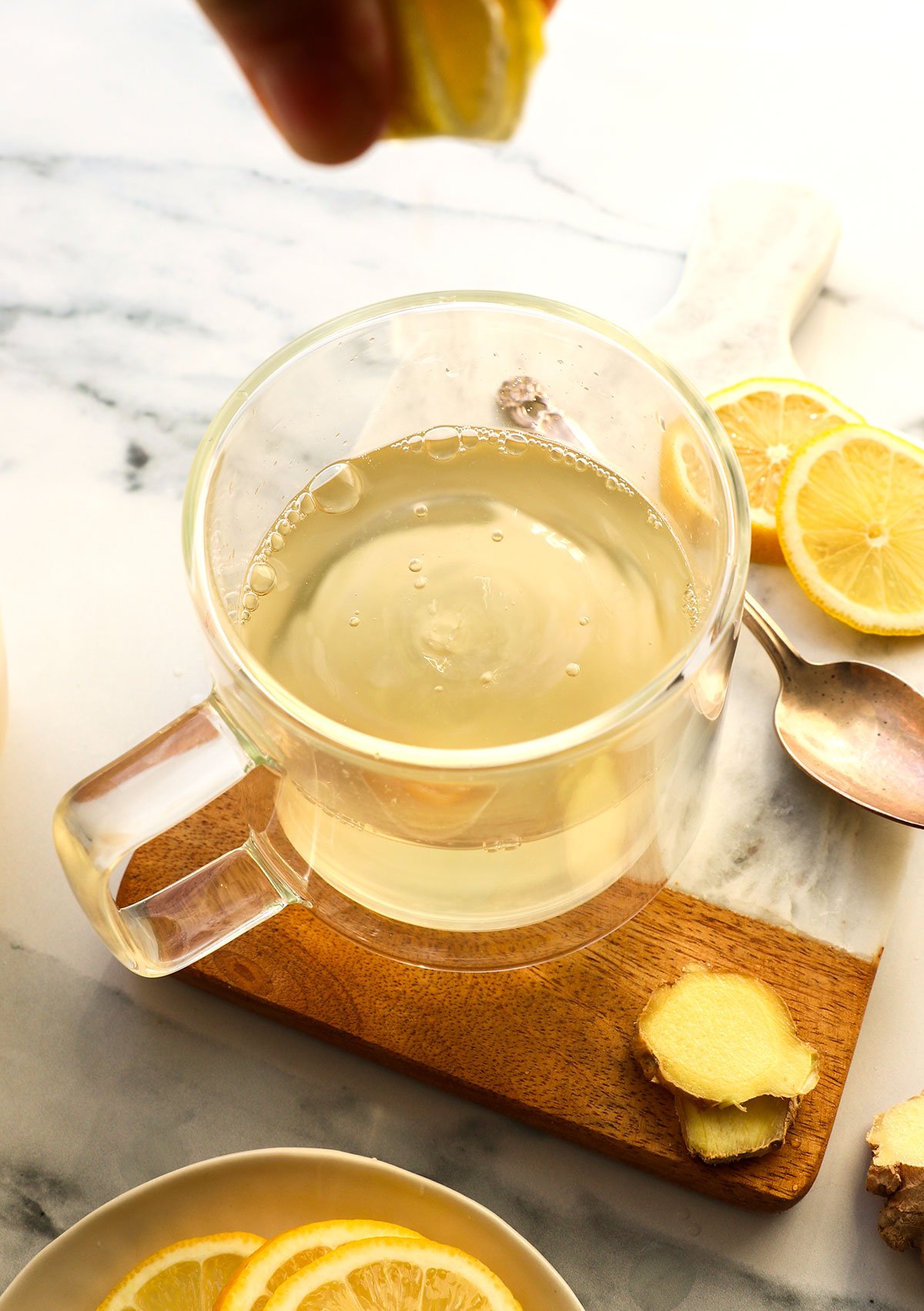 ginger tea in a glass mug with lemon squeezed into it.