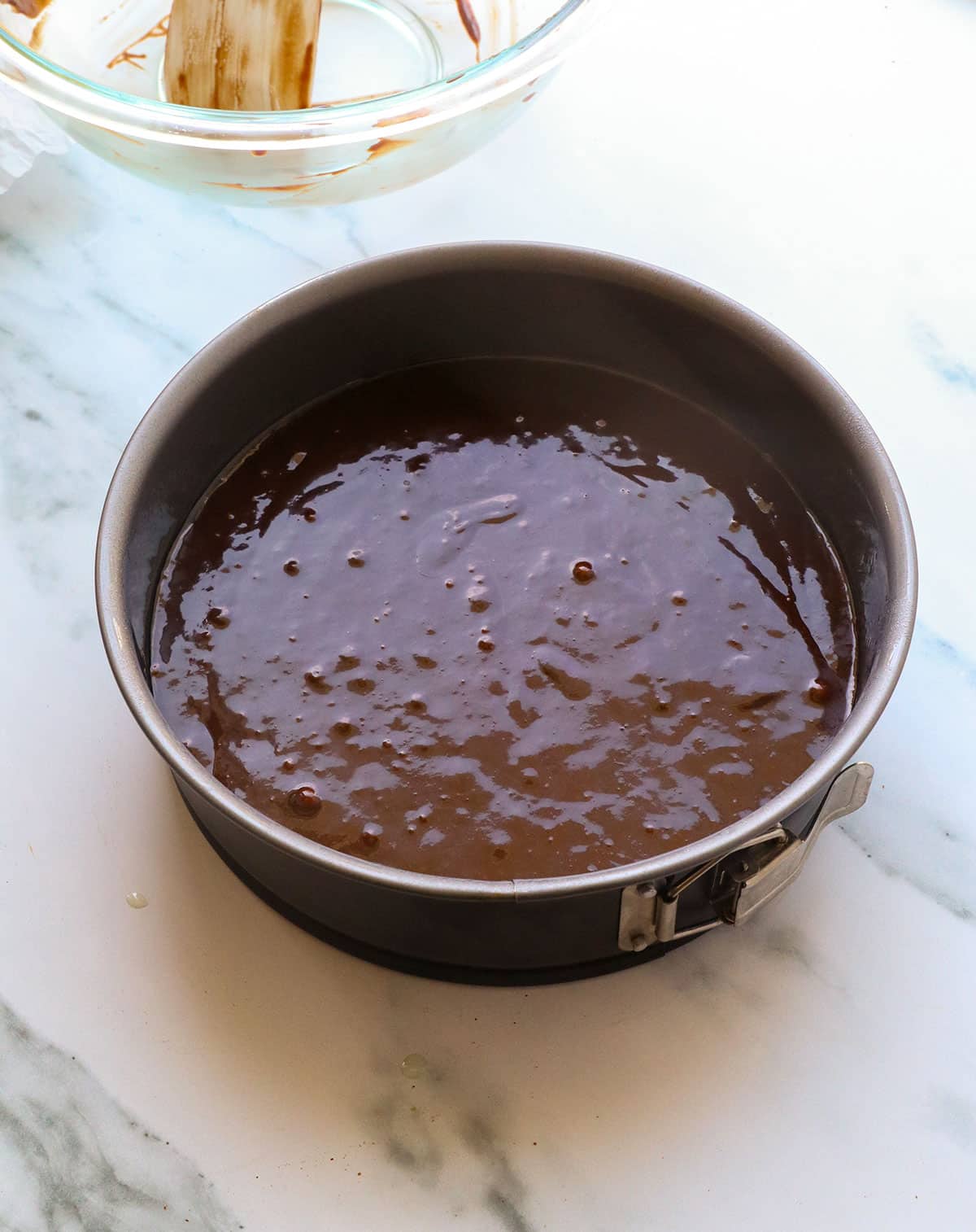 chocolate batter spread out in a springform pan.