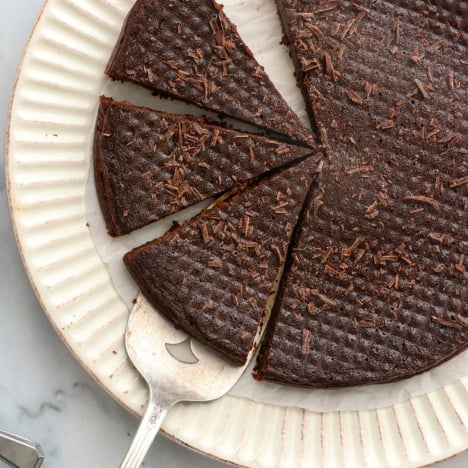 flourless chocolate cake cut into slices with chopped chocolate on top.