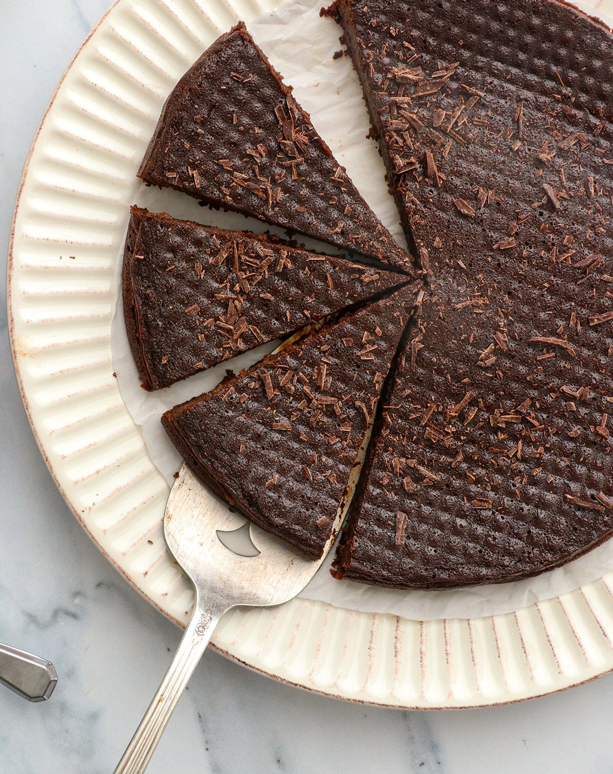 flourless chocolate cake cut into slices with chopped chocolate on top.