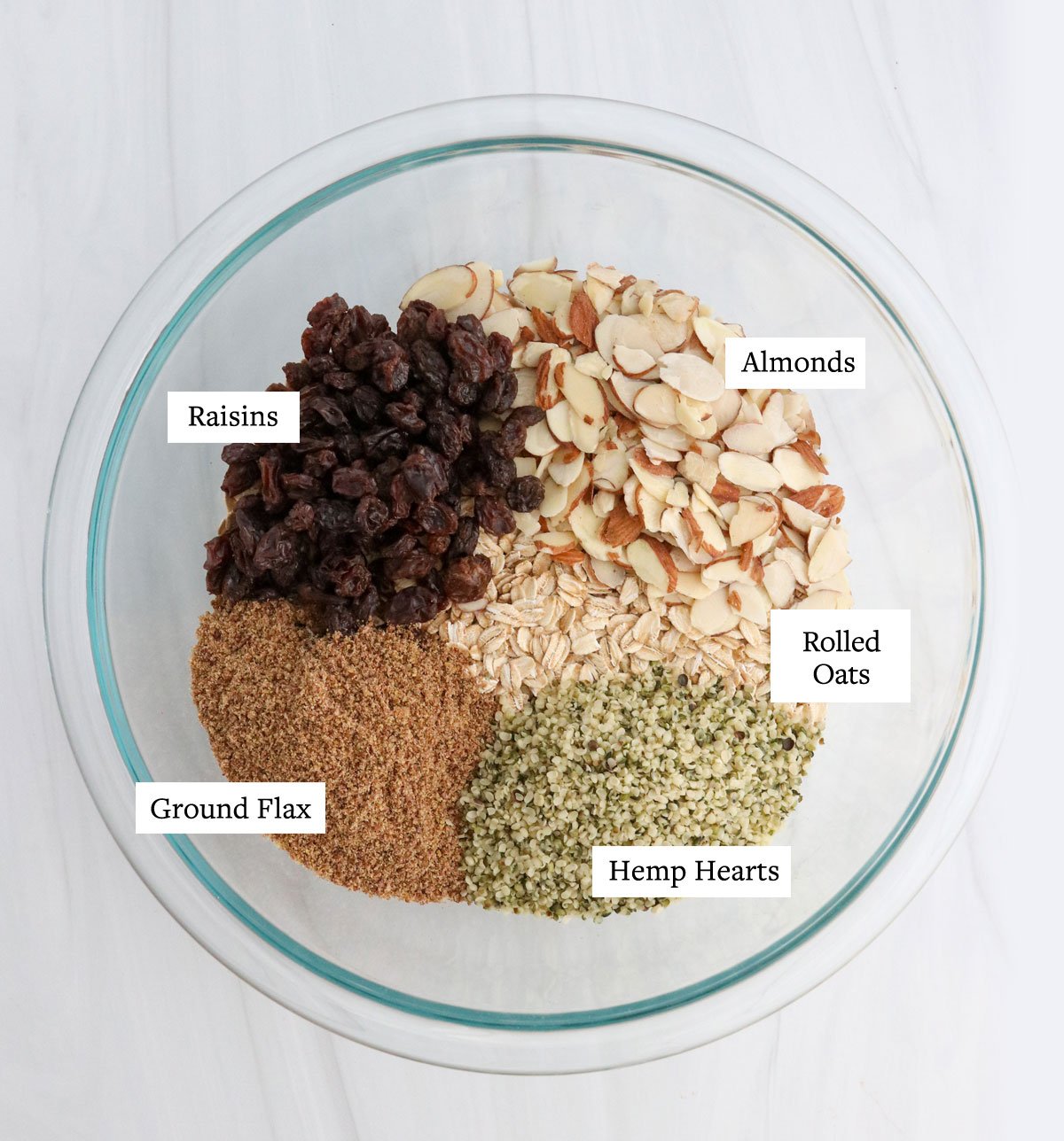 gluten-free muesli ingredients labeled in glass bowl.
