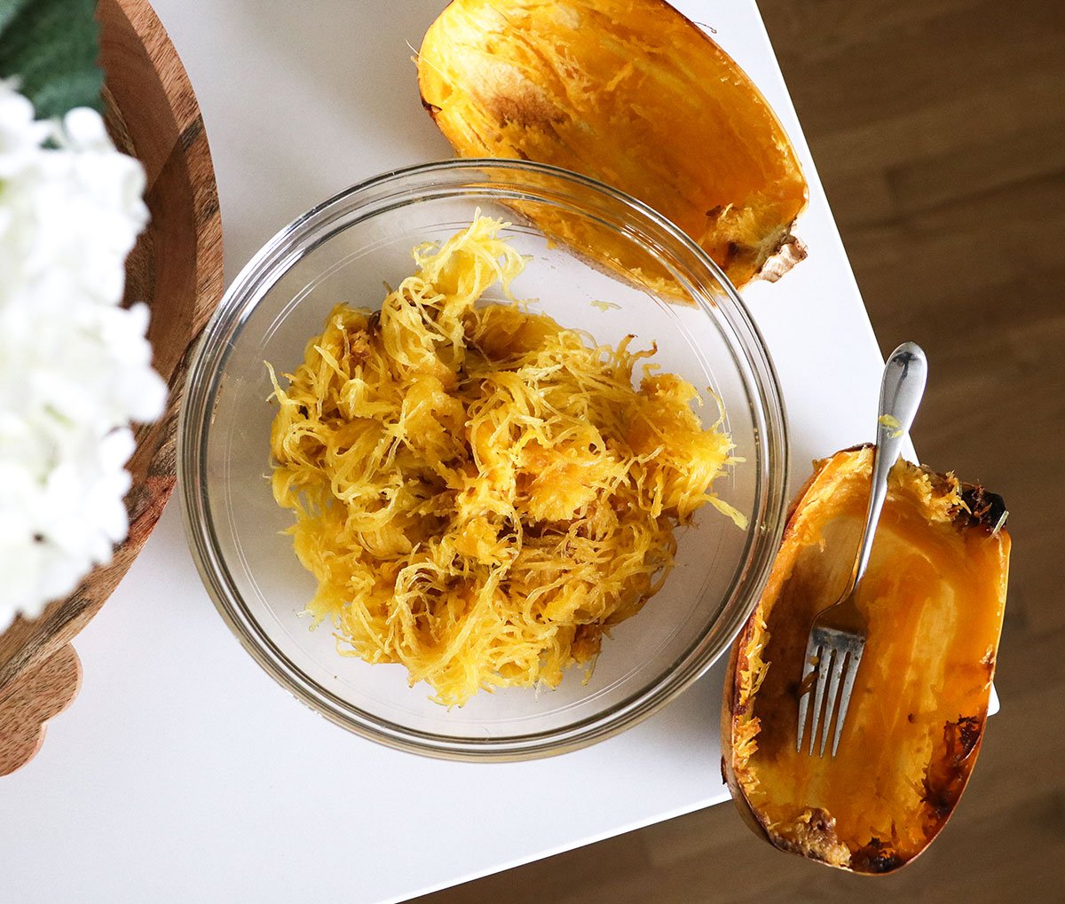 spaghetti squash scraped into a glass bowl from two squash halves.