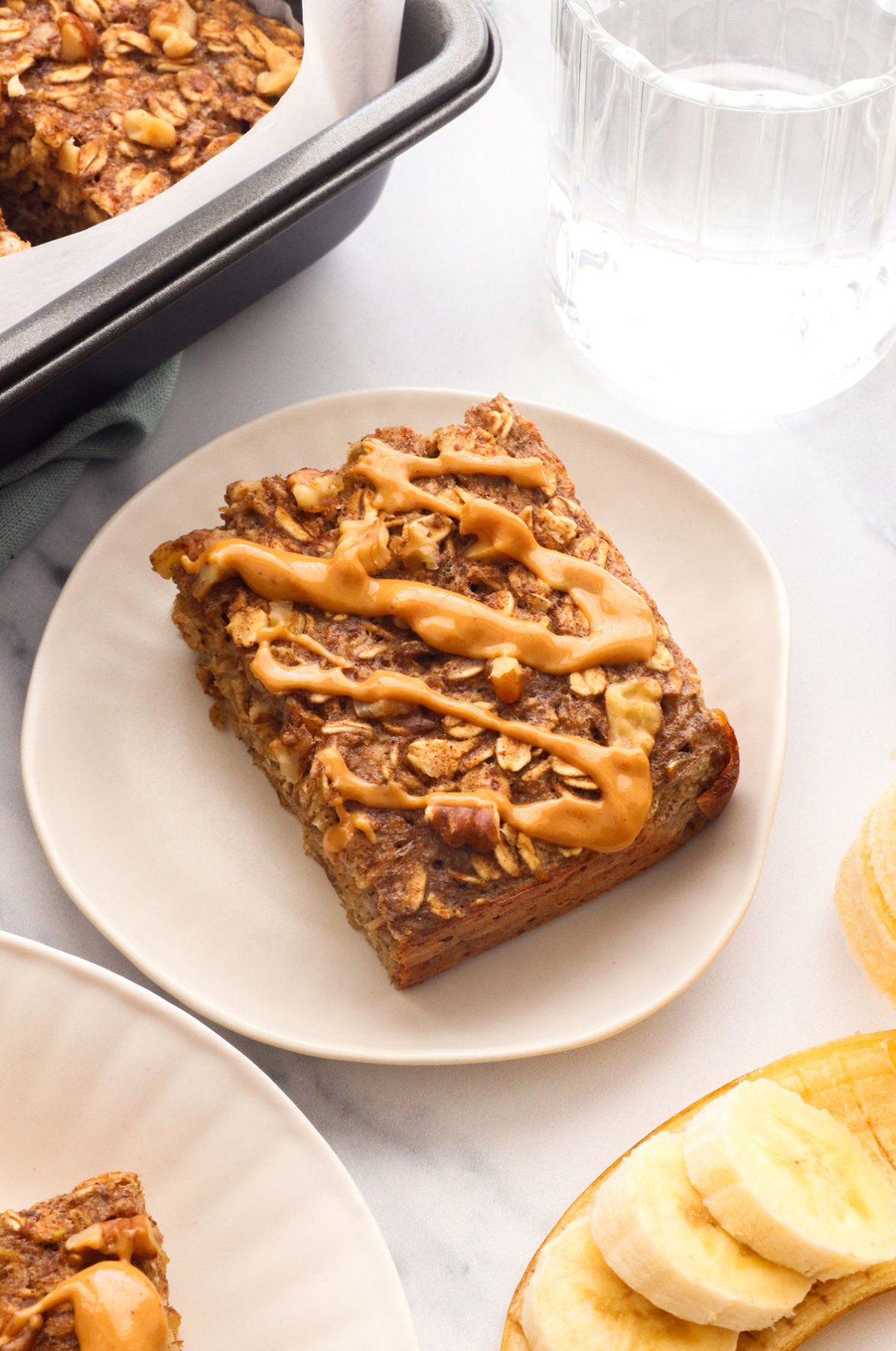 banana baked oatmeal slice with peanut butter on a plate. 