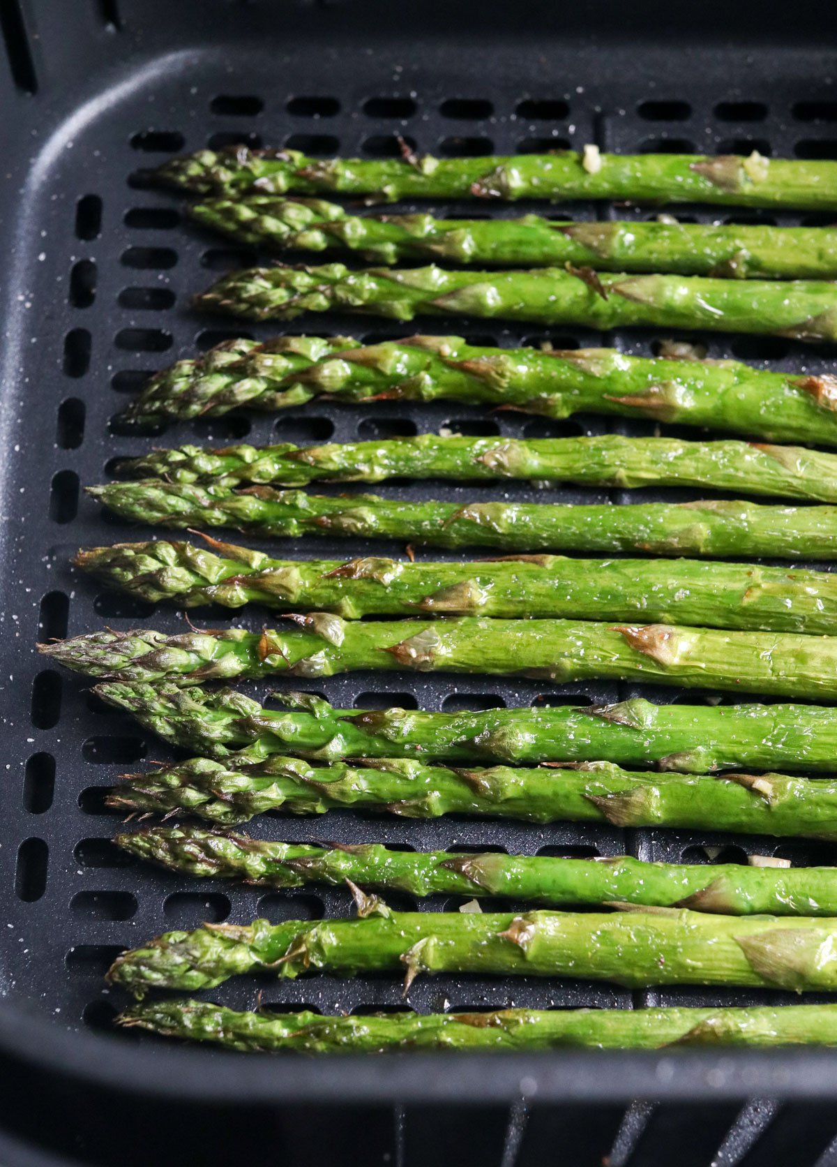 asparagus spears in air fryer basket.