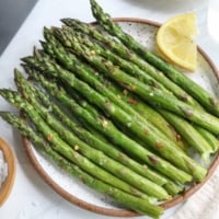 air fryer asparagus served on white plate with lemon.