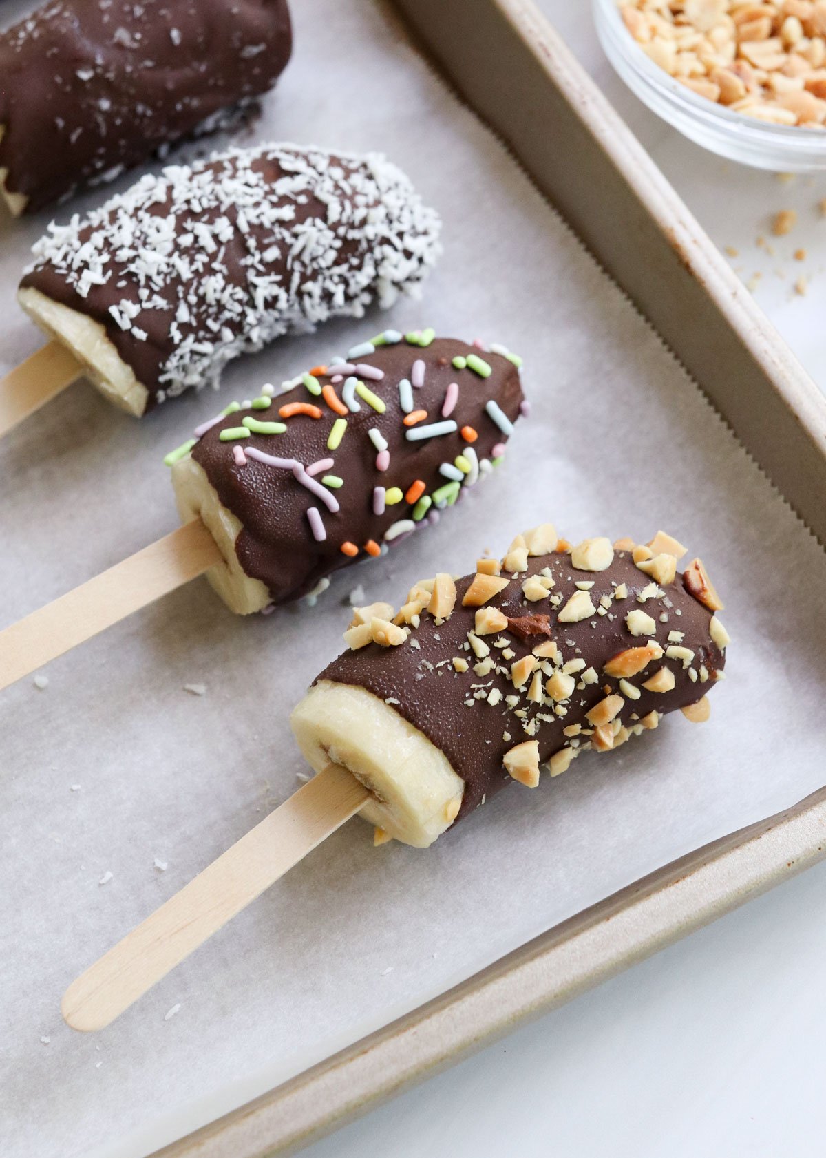 chocolate covered bananas with different toppings.
