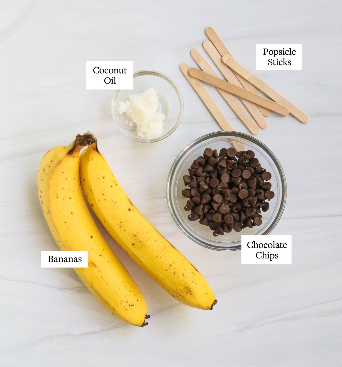 ingredients for chocolate covered bananas labeled on white surface.