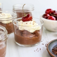 vegan chocolate mousse served with whipped cream and cherry.