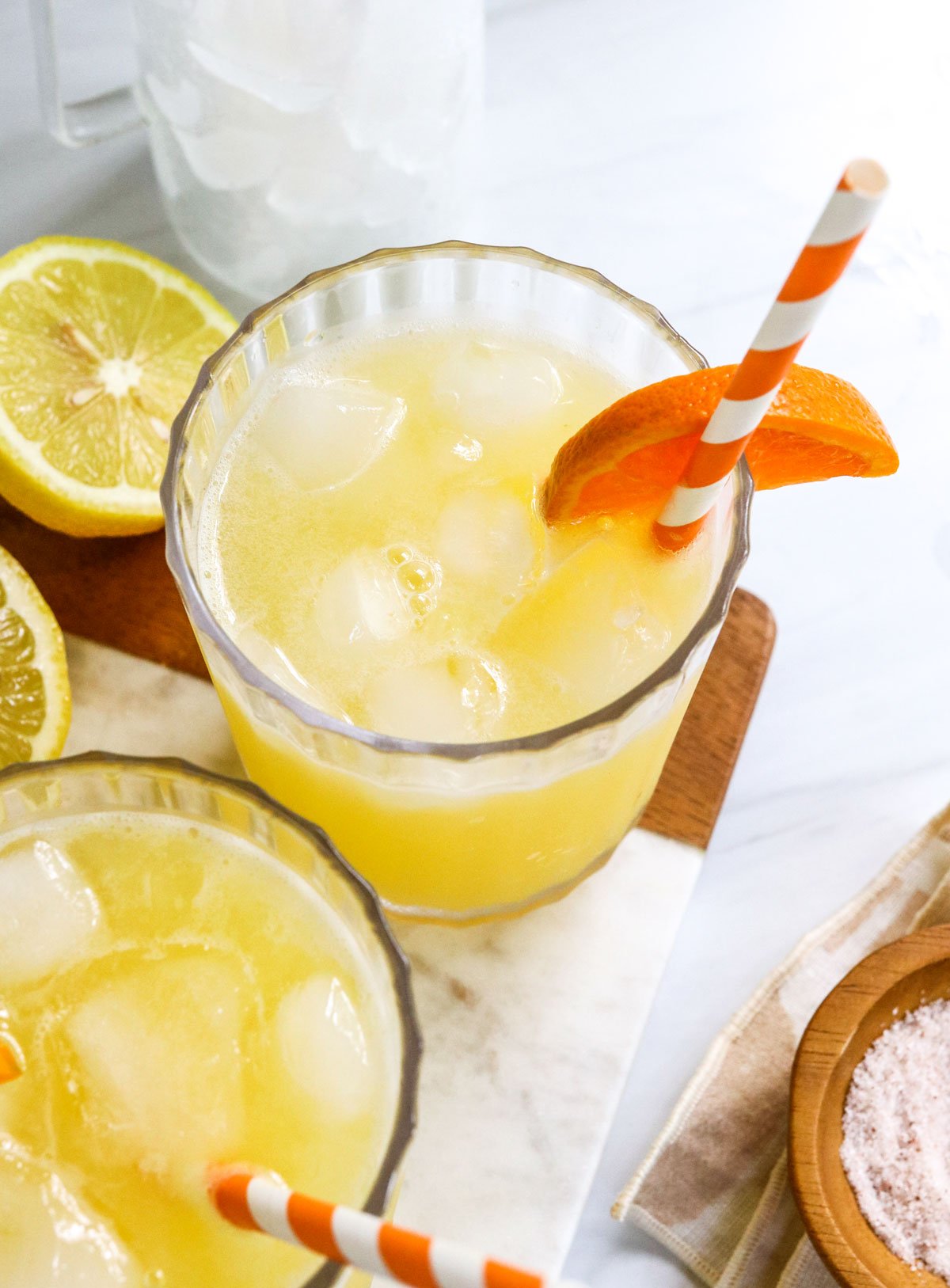 Summer cocktail in glass with orange slice and drinking straw