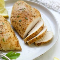 baked chicken breasts sliced on a white plate.