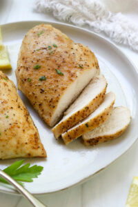 baked chicken breasts sliced on a white plate.