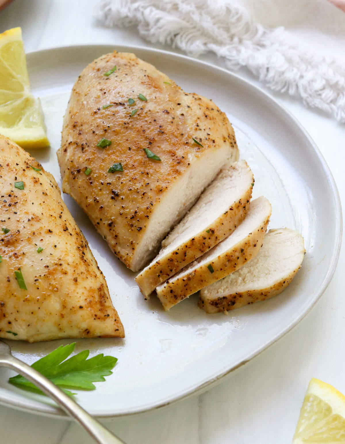 baked chicken breasts sliced on a white plate.