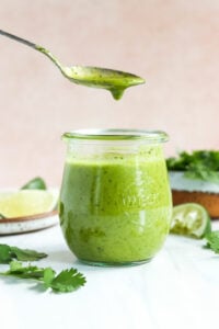 cilantro lime dressing lifted up on a spoon from a jar.