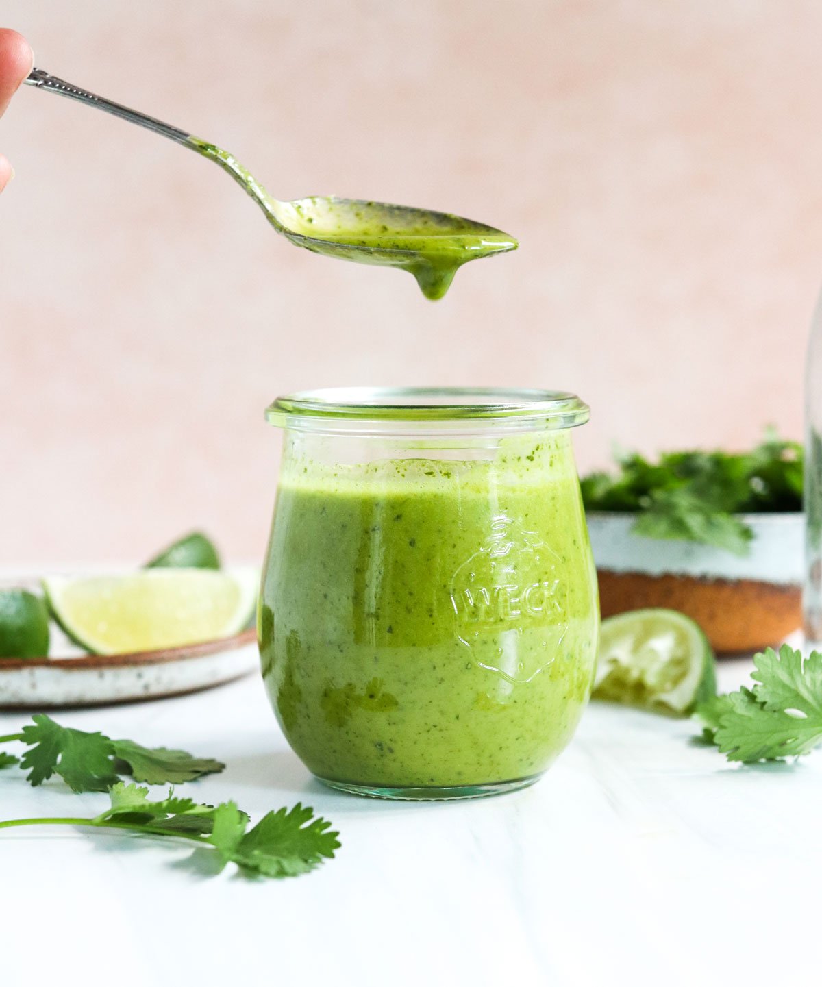 cilantro lime dressing lifted up on a spoon from a jar.