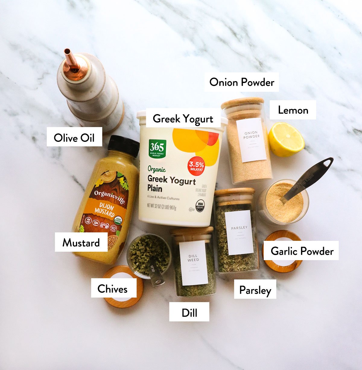 Greek yogurt, mustard, oil, and spices labeled on a white surface. 
