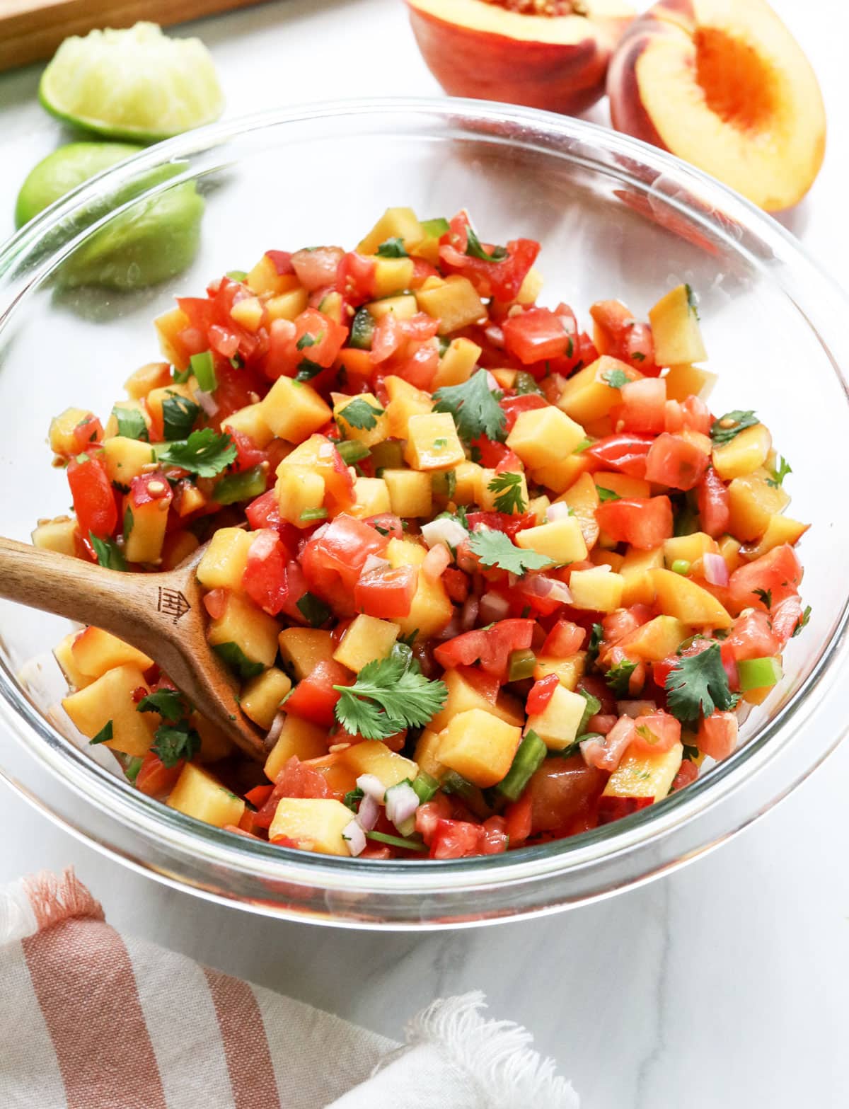 peach salsa in glass bowl with serving spoon.
