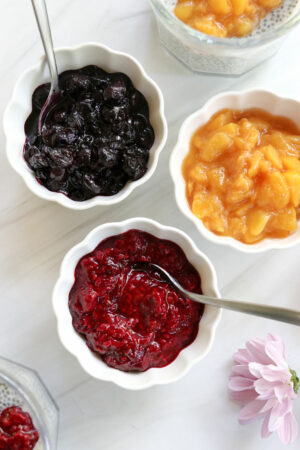 3 different types of fruit compote in bowls with spoons.