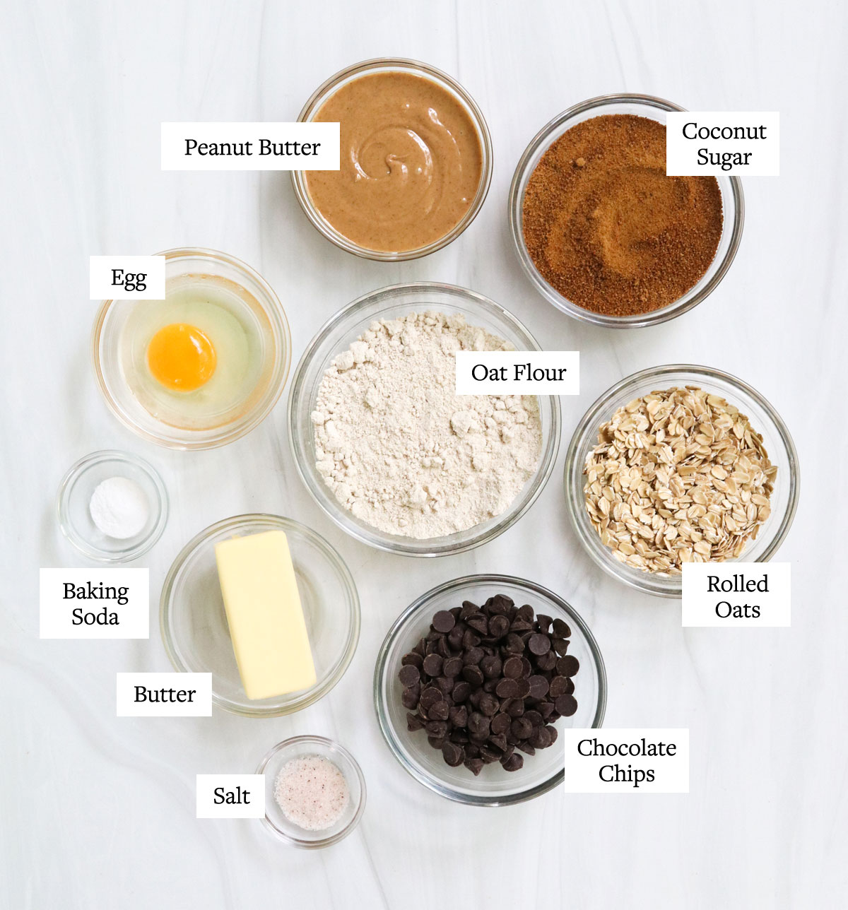 Ingredienti del biscotto di farina d'avena al burro di arachidi etichettati sulla superficie bianca.