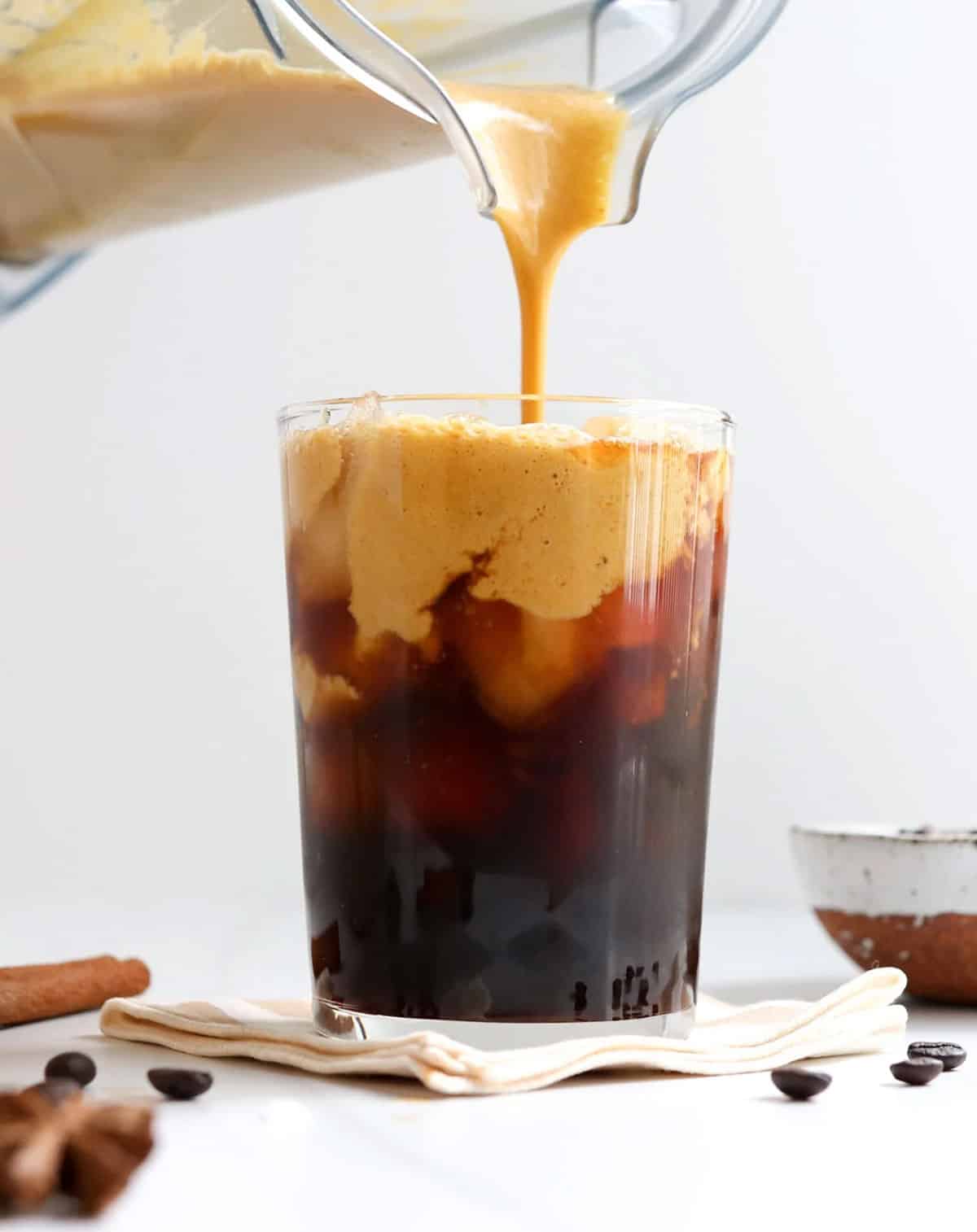 pumpkin creamer poured over a cup of black iced coffee.