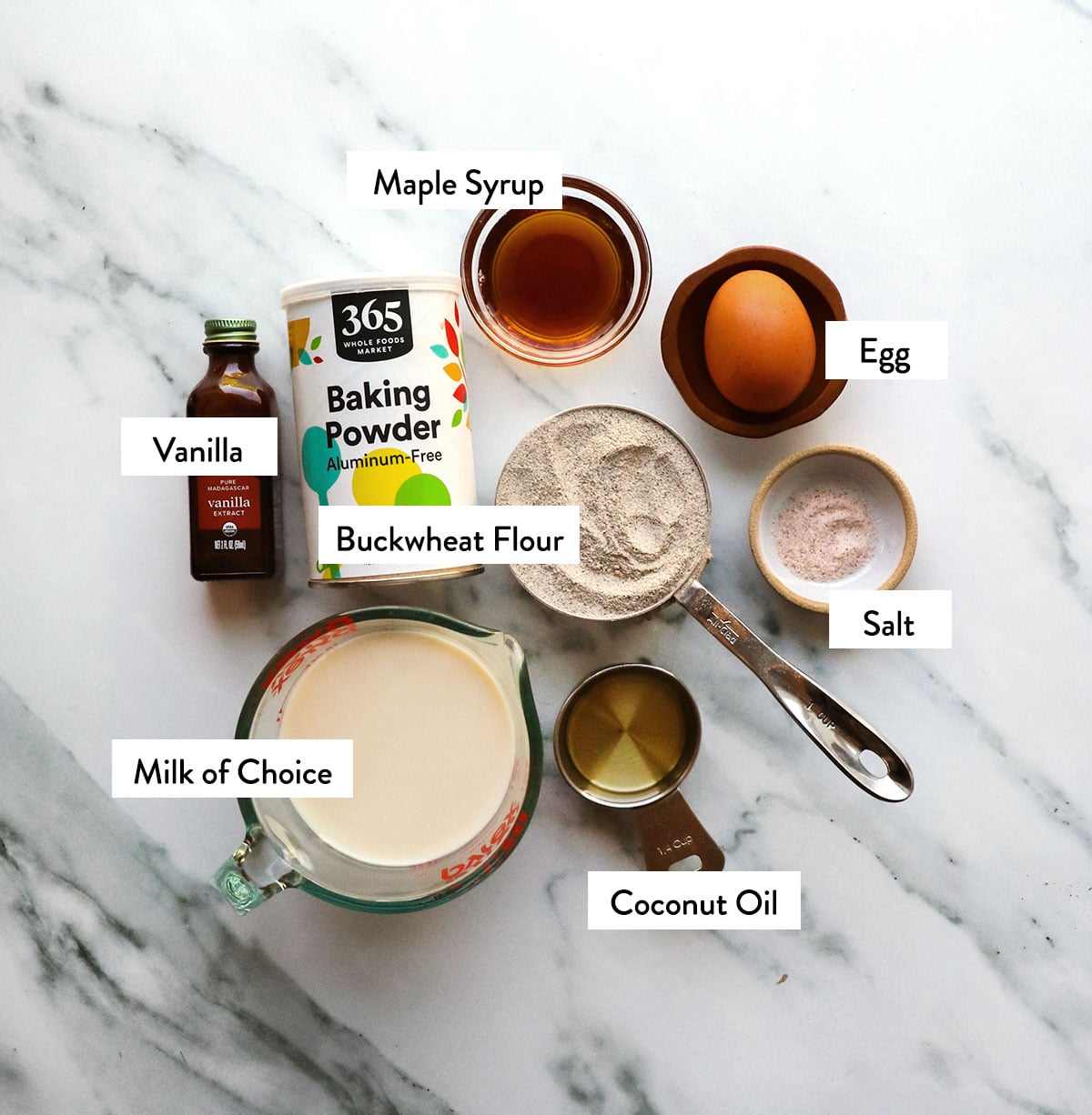 buckwheat flour, milk, egg, maple syrup, and baking powder labeled in bowls. 