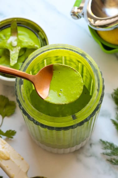 green goddess dressing lifted on a spoon from the blender.