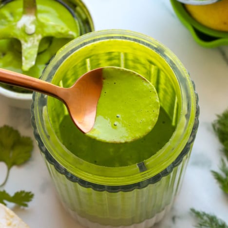 green goddess dressing lifted on a spoon from the blender.
