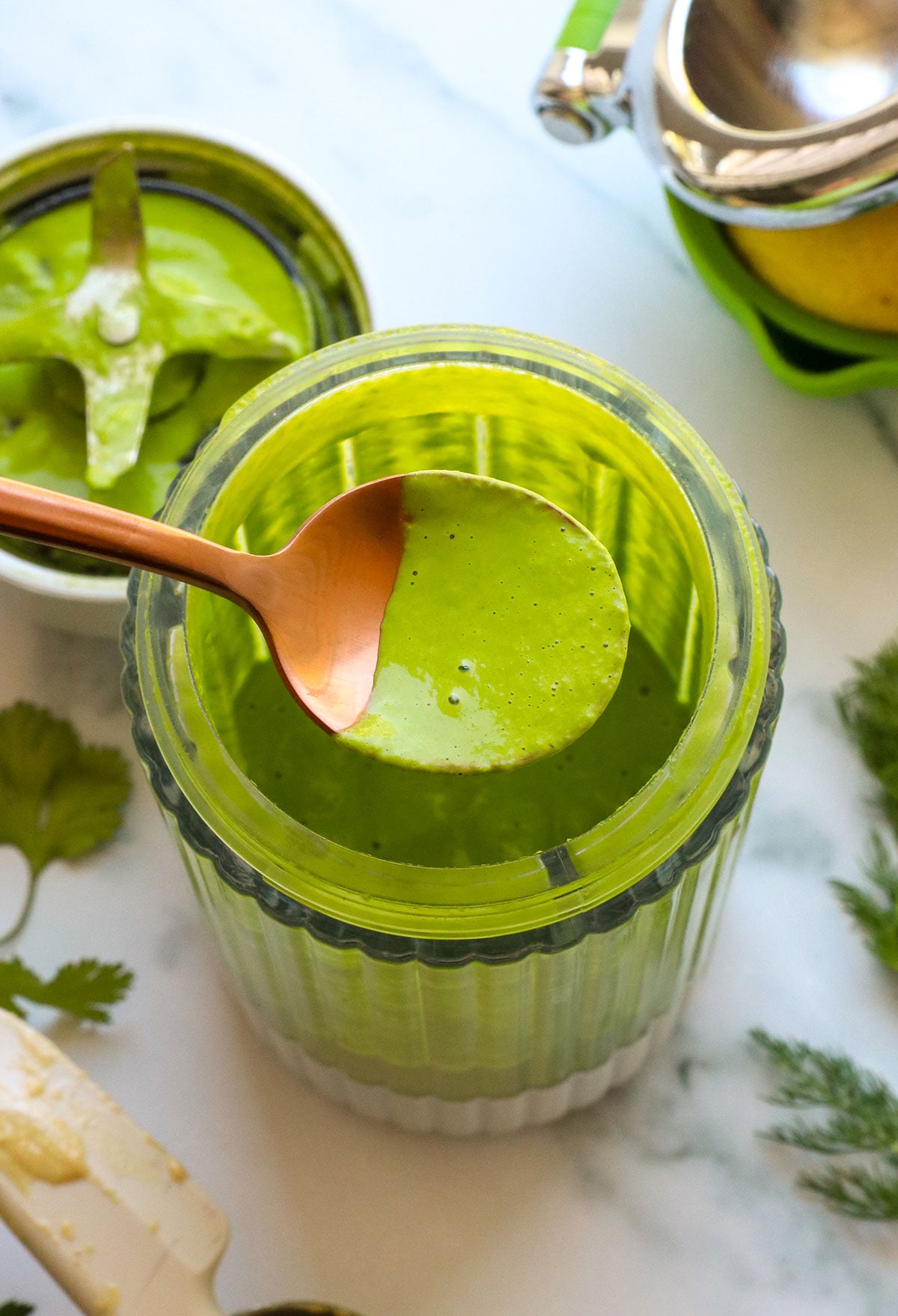 green goddess dressing lifted on a spoon from the blender. 