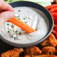 carrot dipped into a bowl of healthy blue cheese dressing.