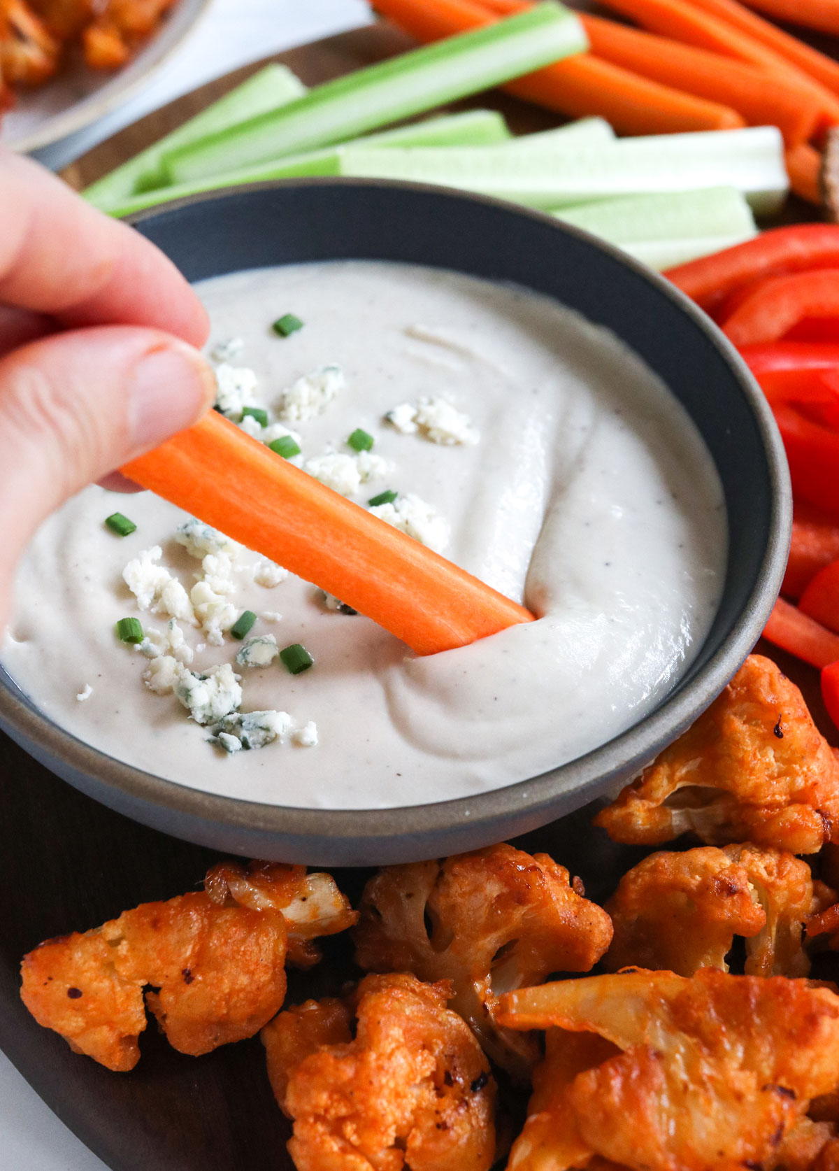 carrot dipped into a bowl of healthy blue cheese dressing.