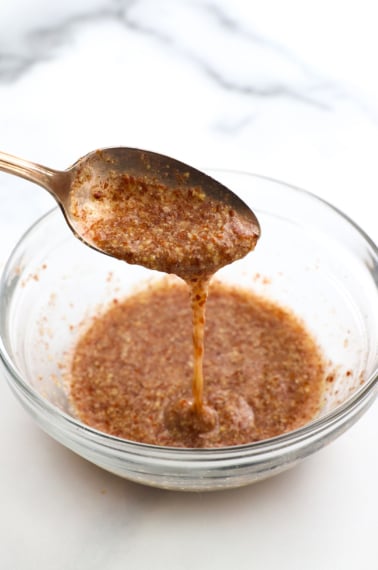 flax egg dripping off a spoon over a glass bowl.