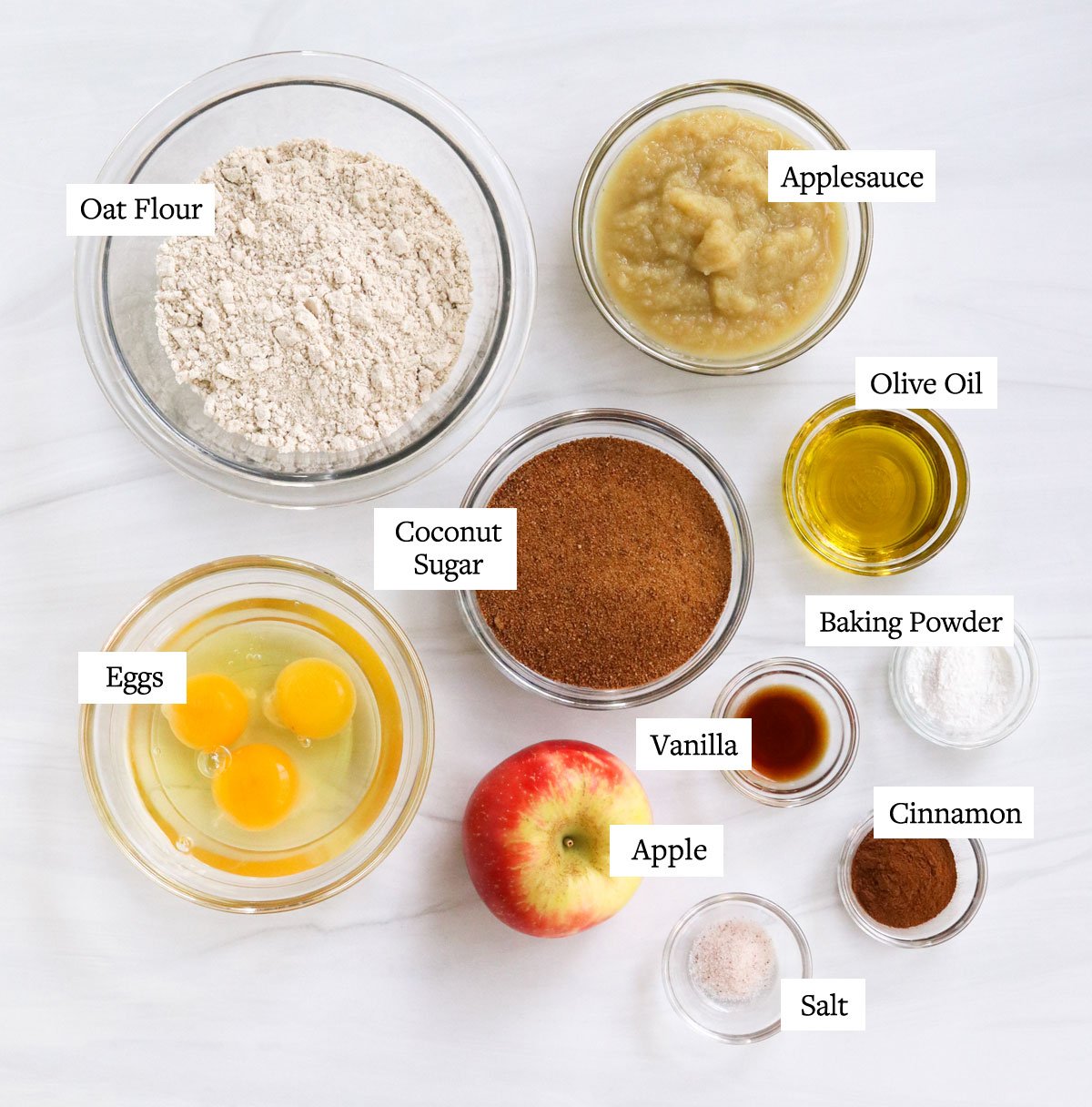 healthy apple muffin ingredients labeled in glass bowls.