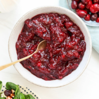 cranberry sauce in a white bowl served with gold spoon.