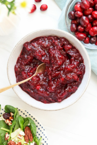 cranberry sauce in a white bowl served with gold spoon.