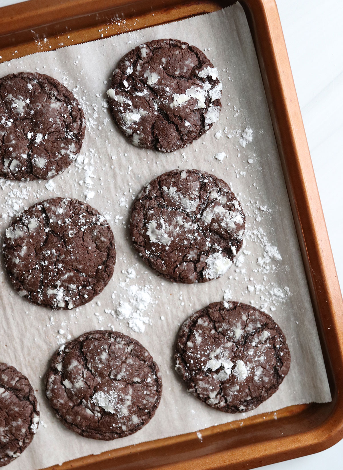 chocolate cookies topped with powdered sugar on pan.