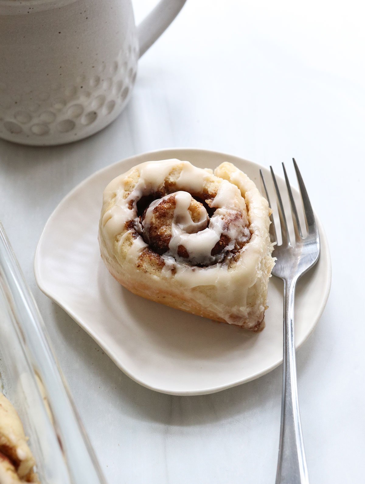 gluten free cinnamon roll served on white plate with fork.