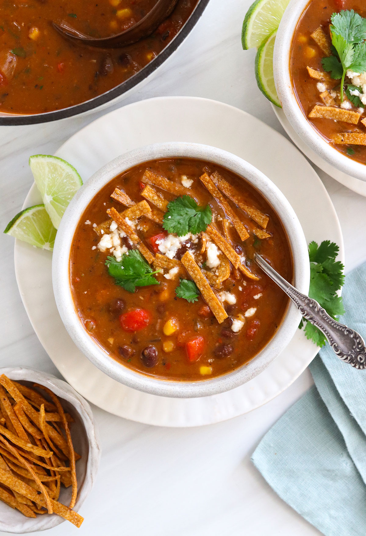 vegetarian tortilla soup served with cheese and cilantro on top.