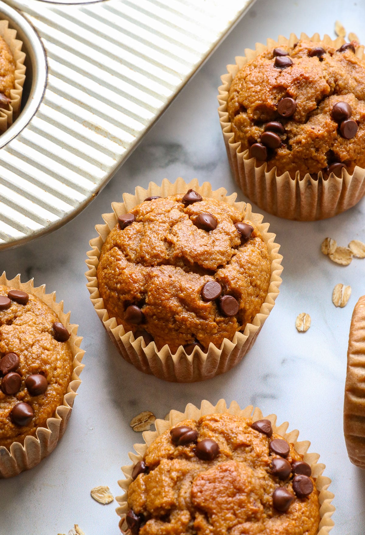 banana oatmeal muffins with chocolate chips on top near the pan. 