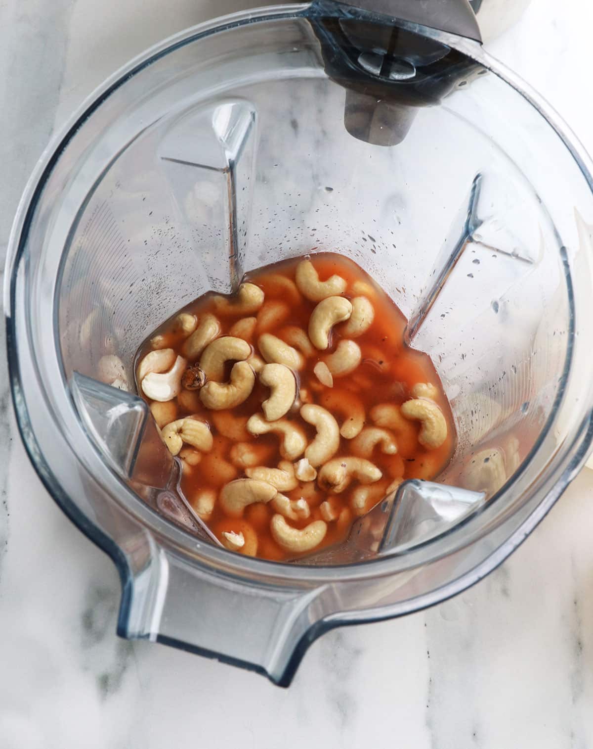 tomato juices poured over cashews in a blender.