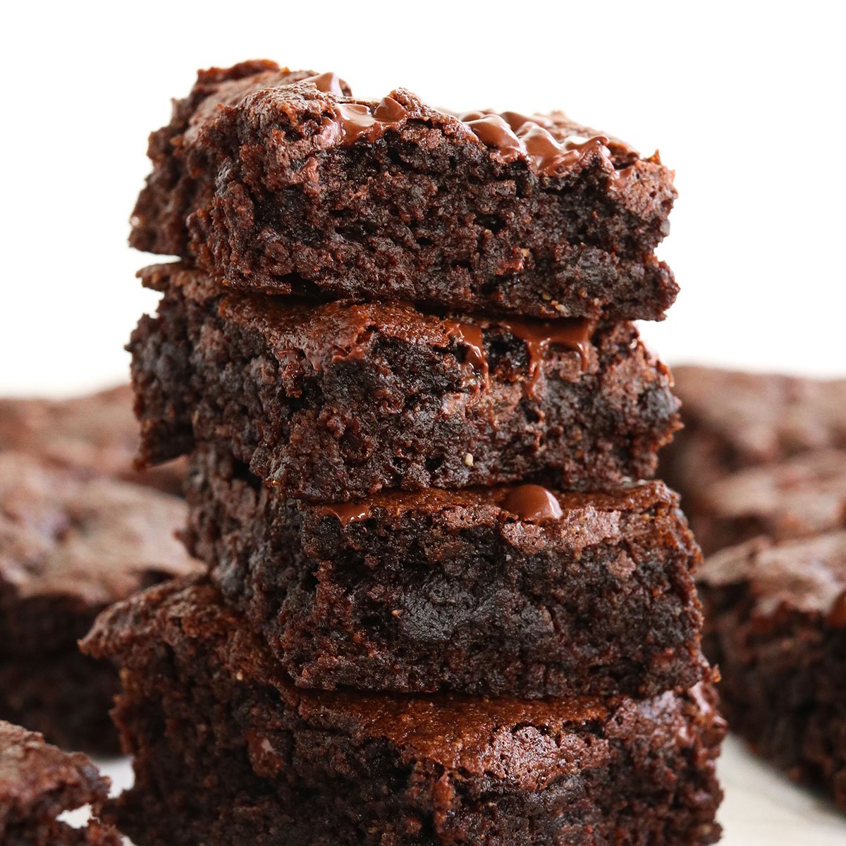 almond flour brownies stacked on a white surface.