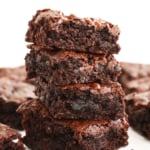 almond flour brownies stacked on a white surface.