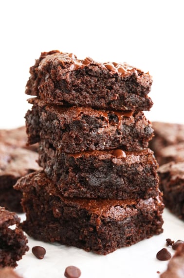 almond flour brownies stacked on a white surface.