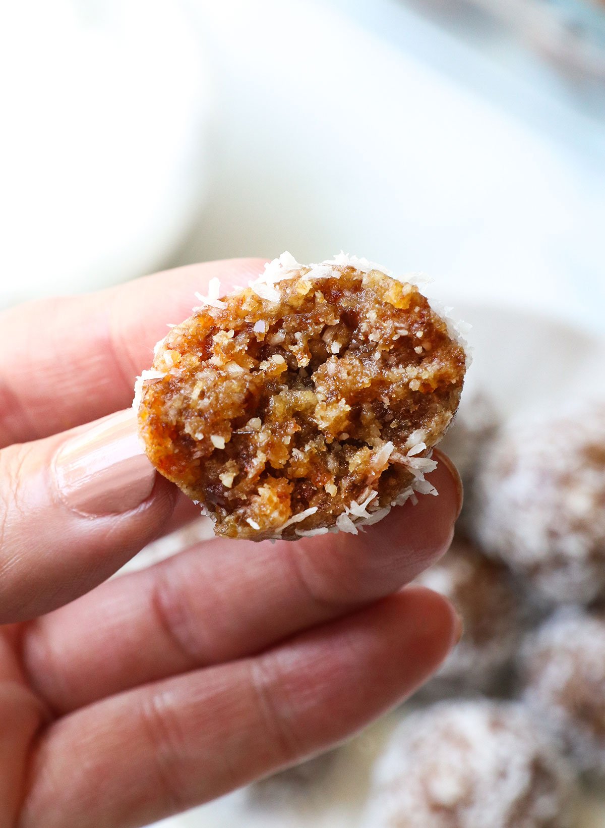 hand holding half of a date energy ball to show the texture. 