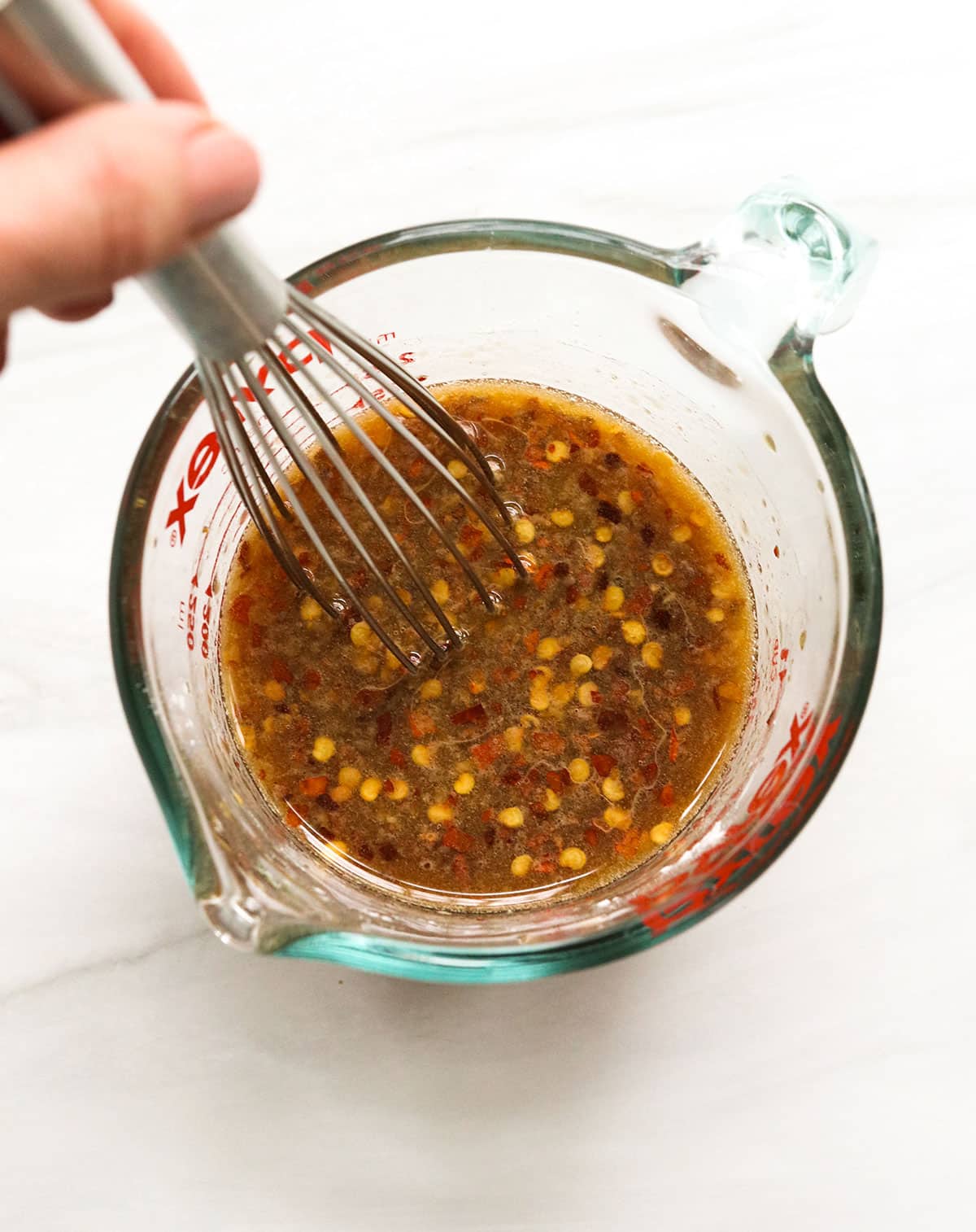 kung pao sauce stirred in a glass measuring cup with a whisk.