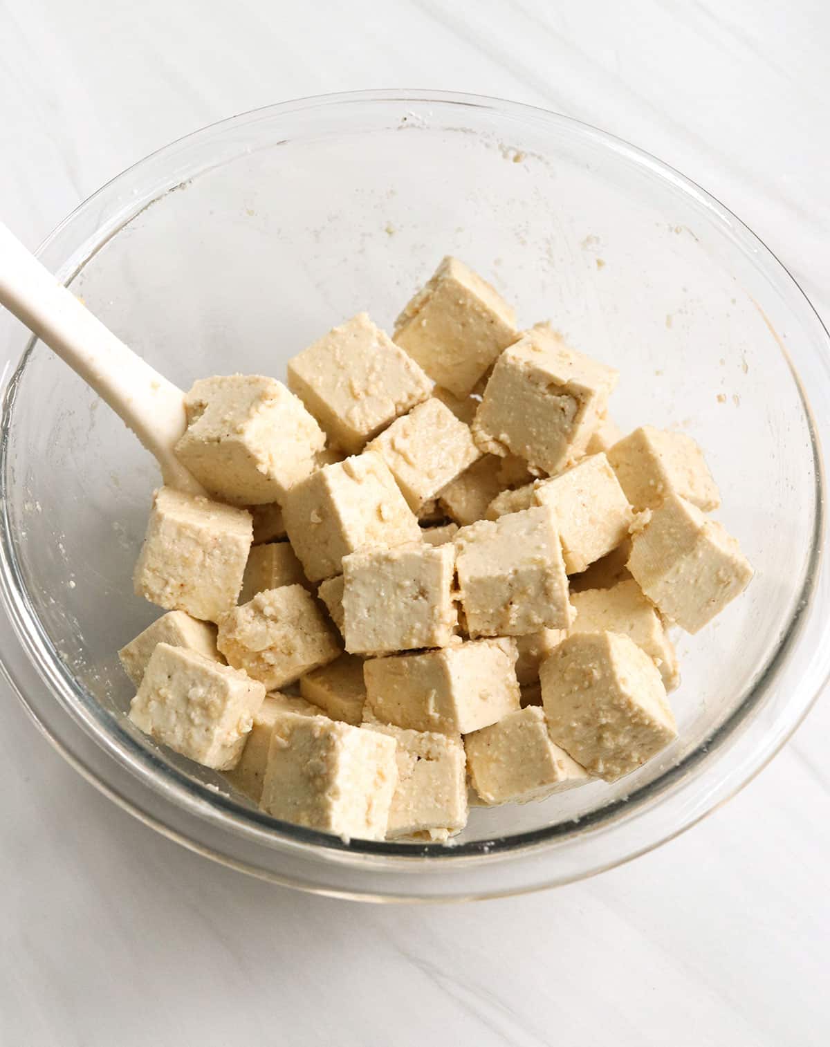tofu stirred in a glass bowl with arrowroot and spices.