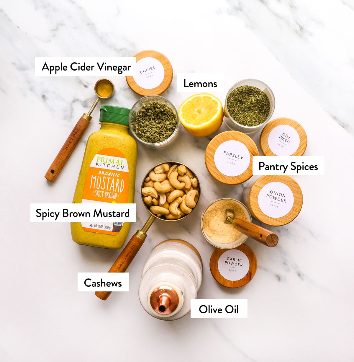 vinegar, mustard, lemon juice, cashews, and spices labeled on a white surface.